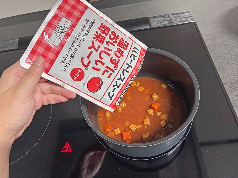 鍋に野菜スープを入れて温めている様子